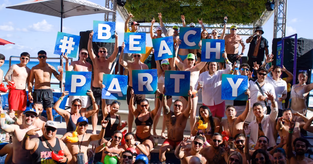 People in swimsuits smile and pose at a pool party, holding blue BEACH PARTY signs with a stage and DJ booth in the background.