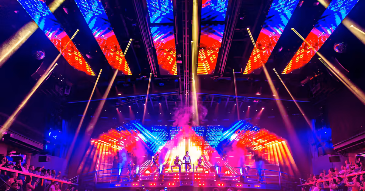 Performers onstage at Coco Bongo Night Club dazzle with colorful lights, lasers, smoke, and lively crowds on both sides.