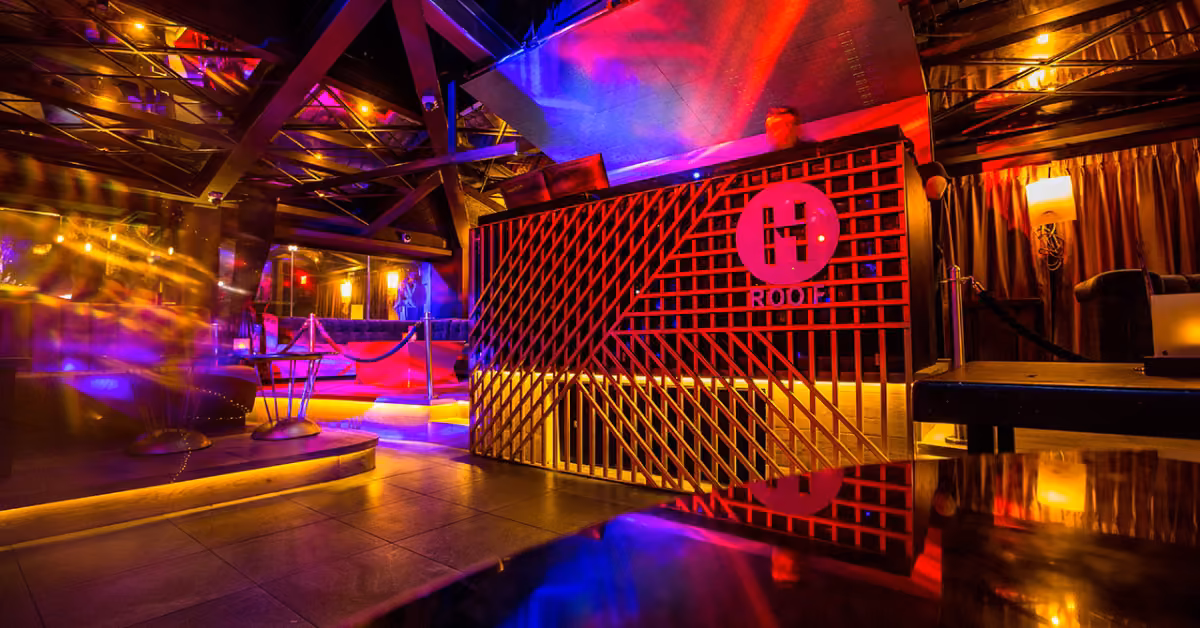Trendy night club with neon lighting, wooden entrance panels, lounge seats, and glossy surfaces for a lively nightlife vibe.