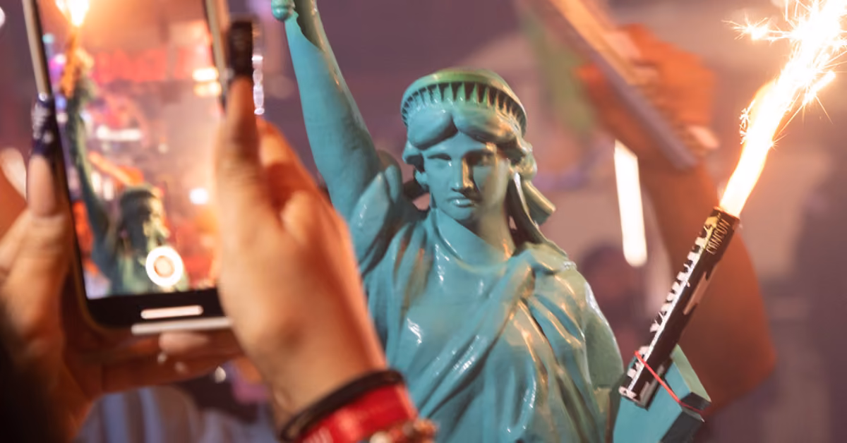 At La Vaquita Night Club, one person holds a mini Statue of Liberty with sparklers as another snaps a photo of the lively scene.