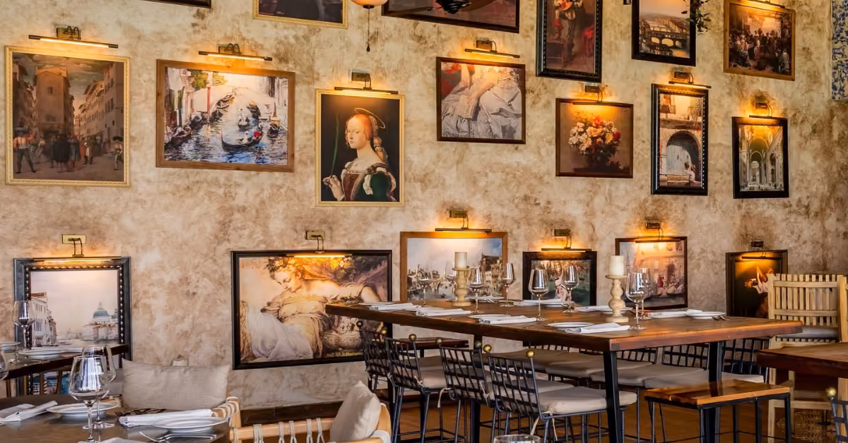 Warmly lit Nicoletta restaurant with framed art, elegant tables, wooden chairs, and a rustic ambiance.