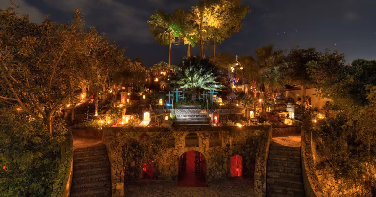 A lush terraced garden glows at night with colorful lights, flanked by stone stairs and tall trees for a mystical vibe.
