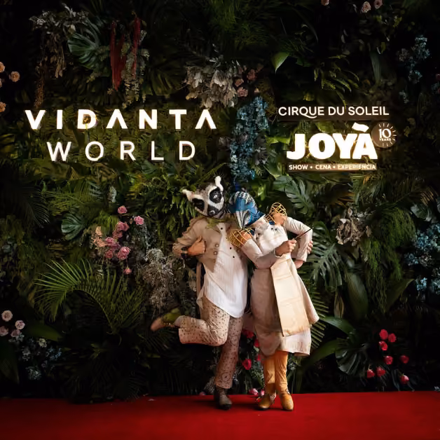 Two performers in animal costumes pose on a red carpet by a flower wall at the Cirque du Soleil JOYÀ 10th Anniversary event.