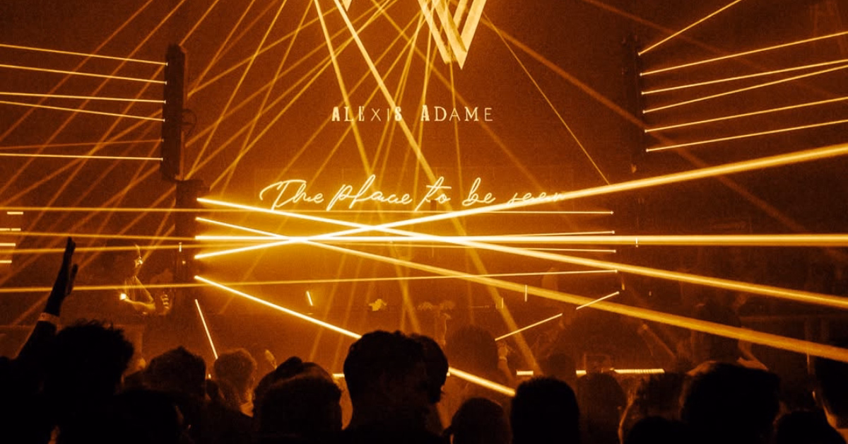 Silhouetted crowd at a nightclub with yellow lasers and glowing text: The place to be seen, capturing the lively atmosphere.
