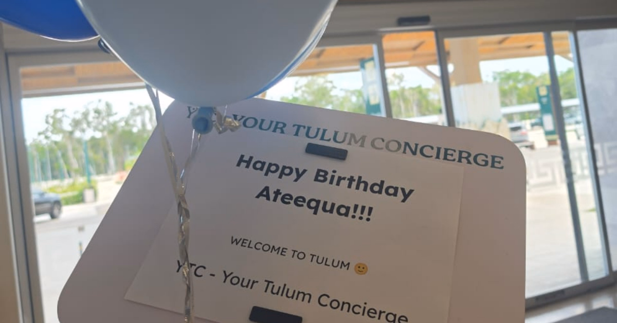 A festive sign with balloons says Happy Birthday Ateequa, Welcome to Tulum. An airport shuttle is visible in the background.