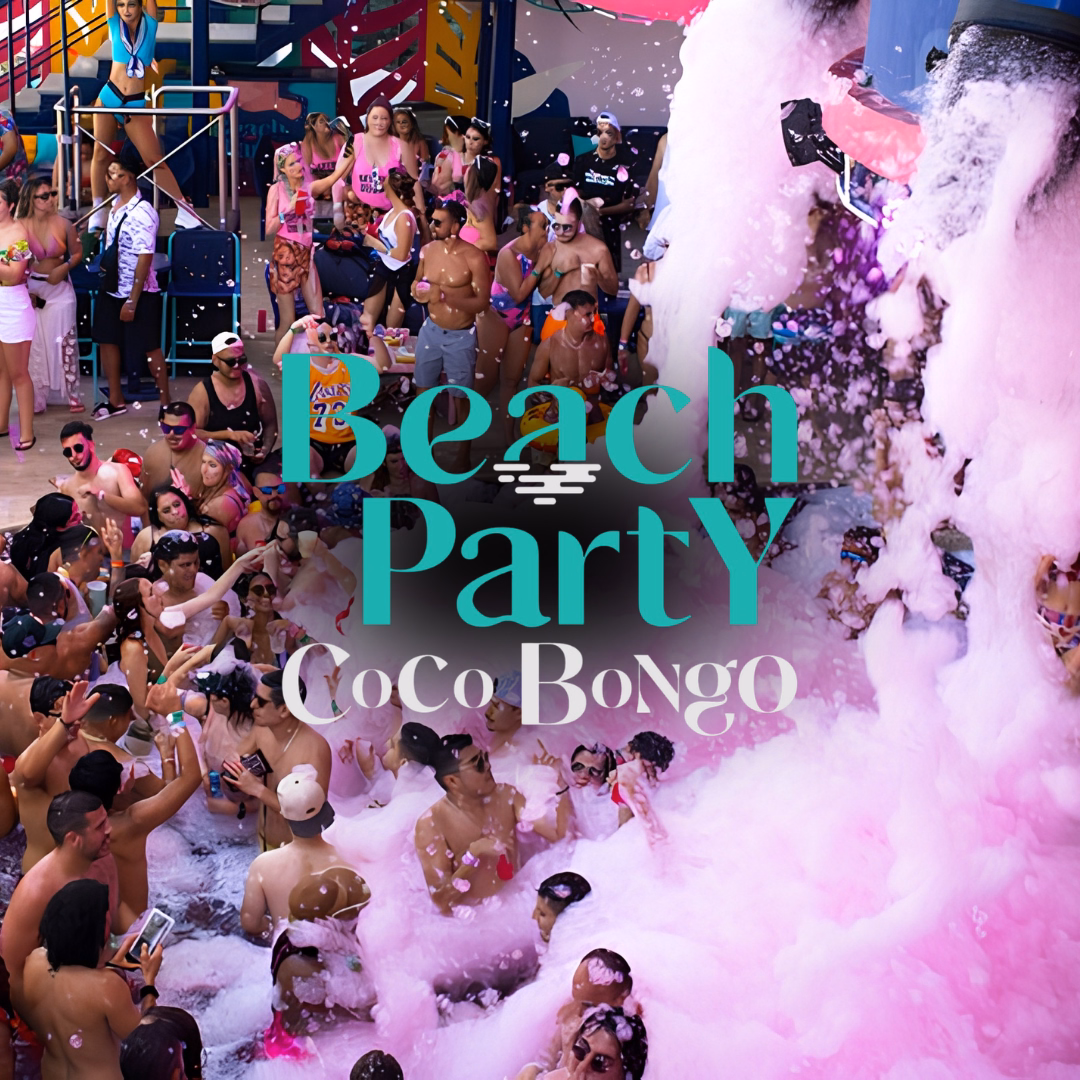 People dance in foam at a vibrant beach party, wearing bright swimwear with festive decorations in the background.