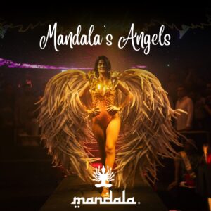 A performer in gold with feathered wings walks on stage at a Mandalas Angels nightclub event, Mandala logo below.